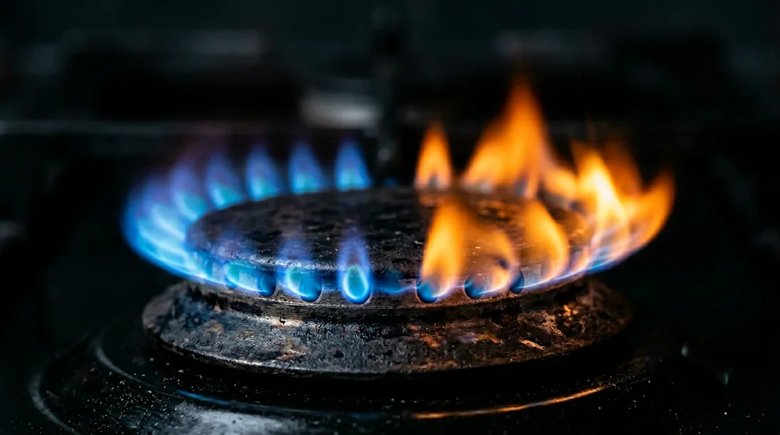 Comparaison visuelle d'une flamme bleue parfaite et d'une flamme orange sur un brûleur de gazinière.