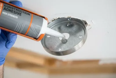 Application de colle de fixation sur le support d'un luminaire