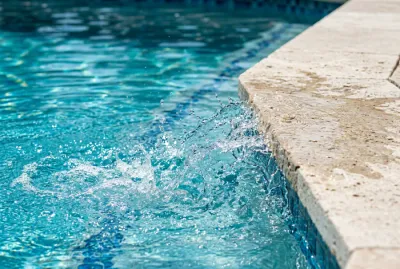 Détail de l'eau claire d'une piscine au sel et sa margelle
